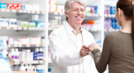 Male pharmacist dispensing a prescription to a female client